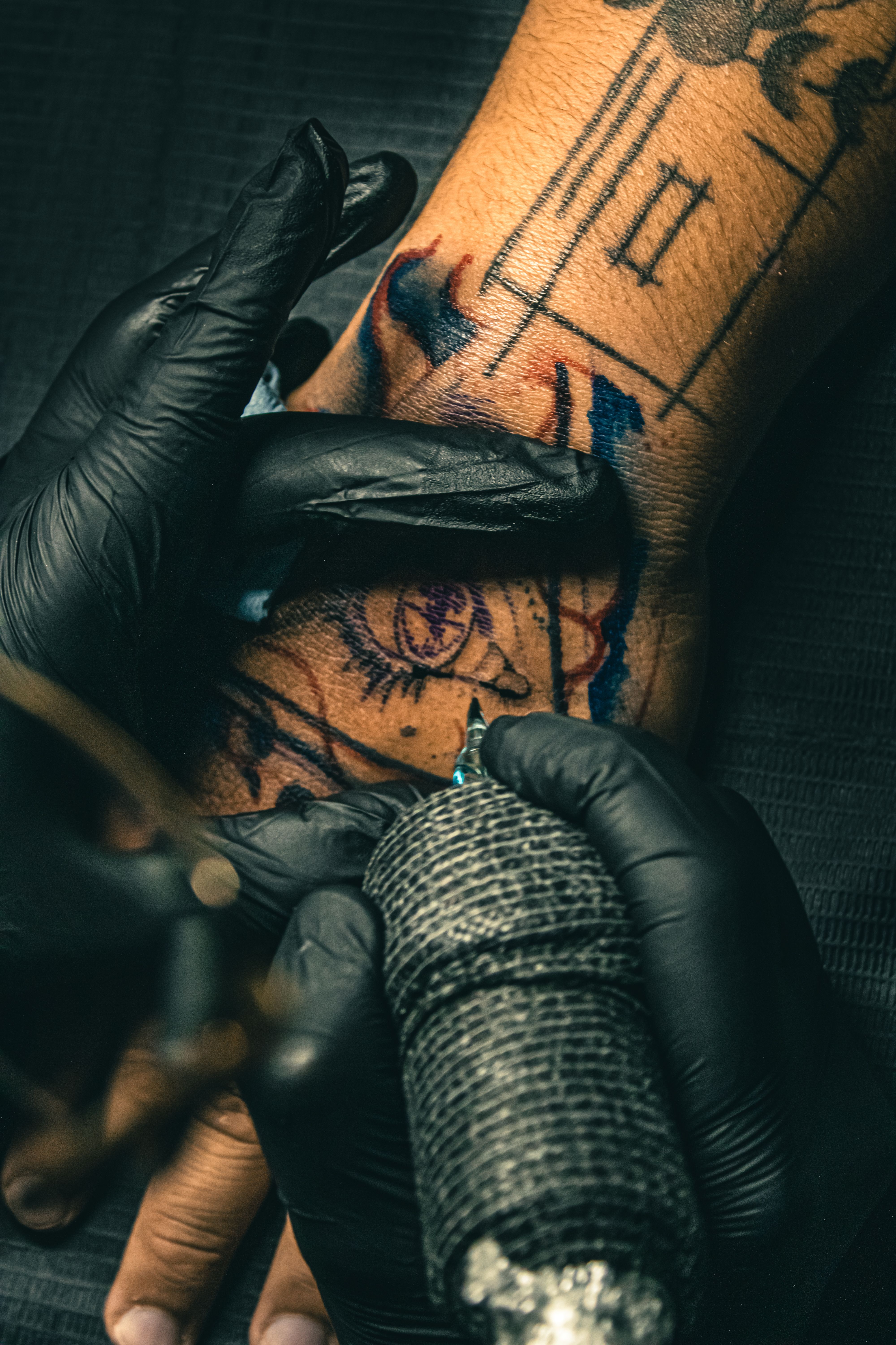 Tatuador realizando sessão de tatuagem colorida na mão